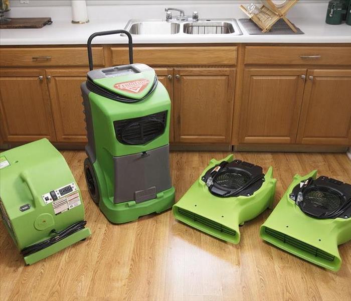 SERVPRO equipment lined up on a vinyl faux wood floor.