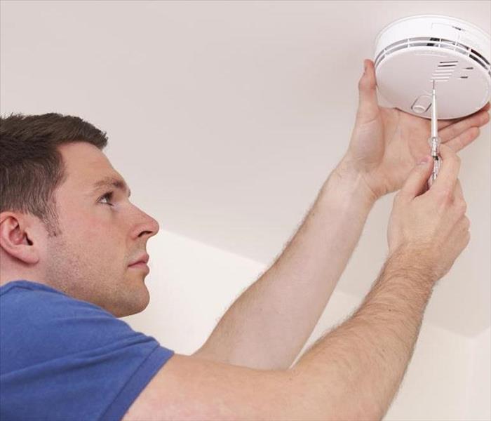 Man changing the batteries in his smoke detector.